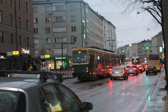車と路面電車が走っている雨のヘルシンキの街並みの写真
