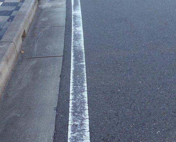 車道上の、消えかかっている道路区画線(白線)の写真