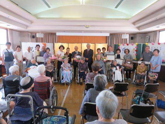 100歳を迎えた19名の高齢者たちを祝っている写真