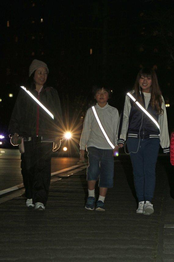 夜光反射材を着用して夜間のウォーキングをしている2人の女性と子供の写真