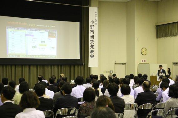 スクリーンの前に沢山の参加者が座っている小野市研究発表会の様子の写真