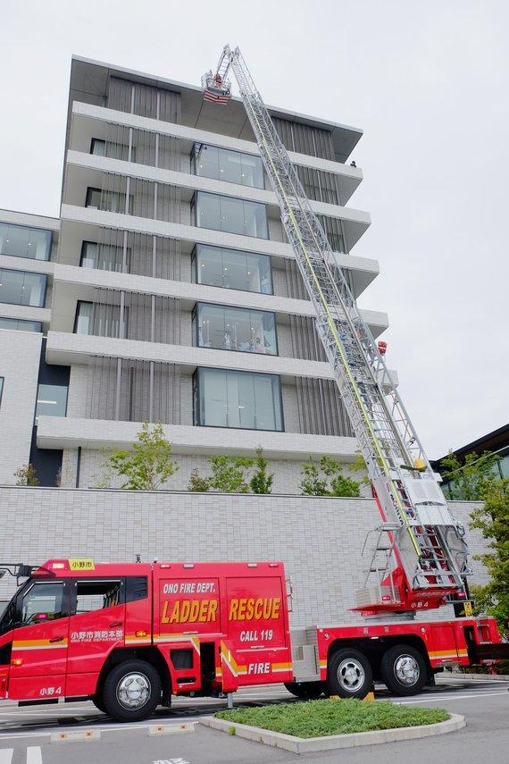 消防はしご車が7階建ての建物で救助訓練している様子の写真