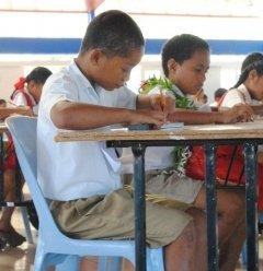 机に向かって鉛筆を握り、一生懸命勉強している男の子の写真
