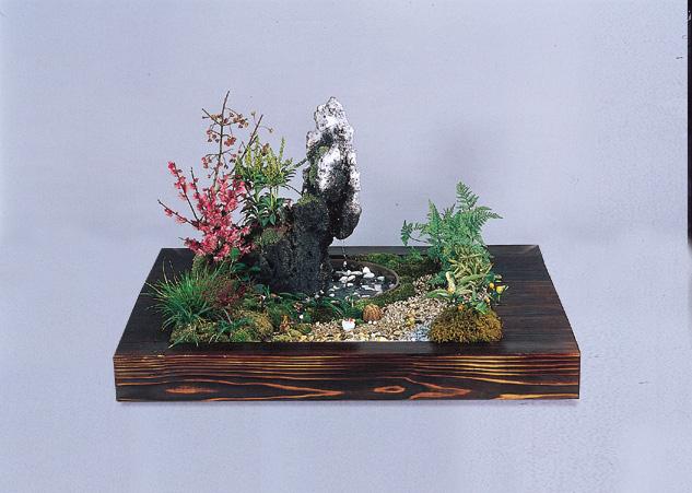 濃い木目の台座に梅や苔、岩などを配置し枯山水を表現したジオラマの写真