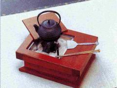 小さな囲炉裏の五徳に鉄瓶がのり傍らに鉄ベラと鉄箸が置かれている写真