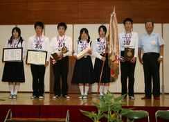 優勝トロフィーや賞状を掲げて並ぶ県立浜松商業高等学校生徒たちの写真