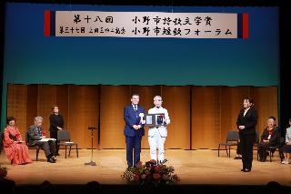 ステージ上で、市長から賞状を受け取る受賞者の写真