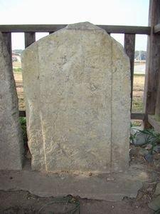 柵で囲われ底石の上にのせられた阿弥陀三尊種子板碑の写真