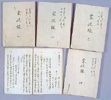 毛筆で書き記された手綴じの本が六冊並べられた写真