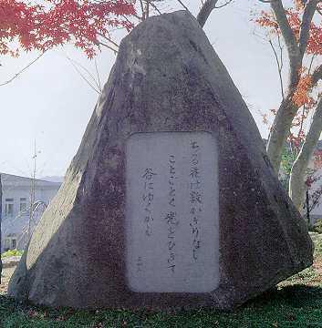 赤い紅葉を背景に、「ちる花は數かぎりなし ことごとく光をひきて 谷にゆくかも」と歌が刻まれた石碑の写真