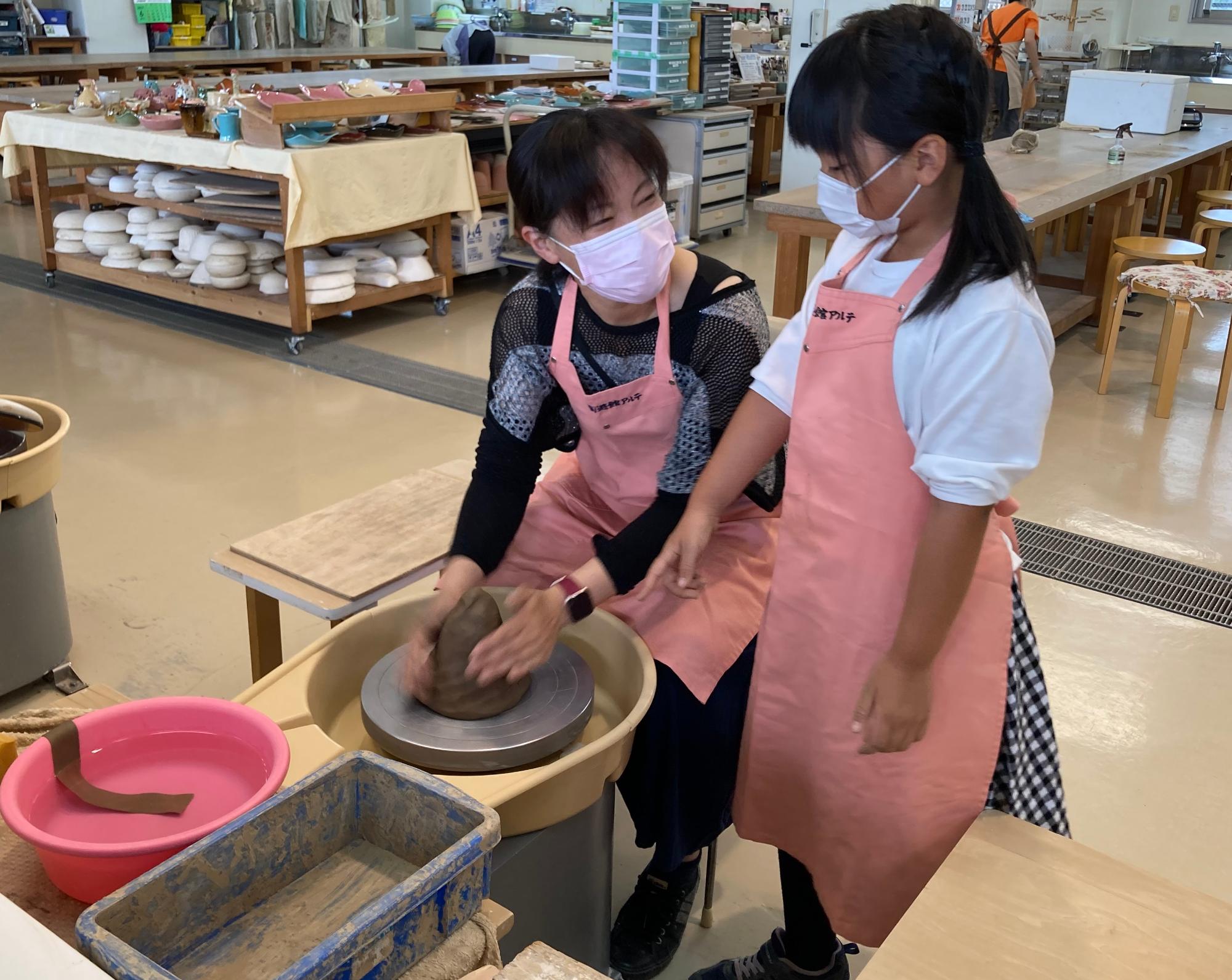 親と子で電動ろくろを体験している画像