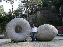 ドーナツ状の石とボール状の間に立っている男性の写真