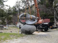 ボール状の台座の上にメビウスの輪のような形になった岩を載せている写真