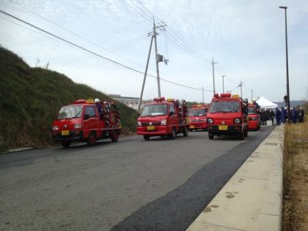 複数の小型の赤い消防車が道路を走っている写真