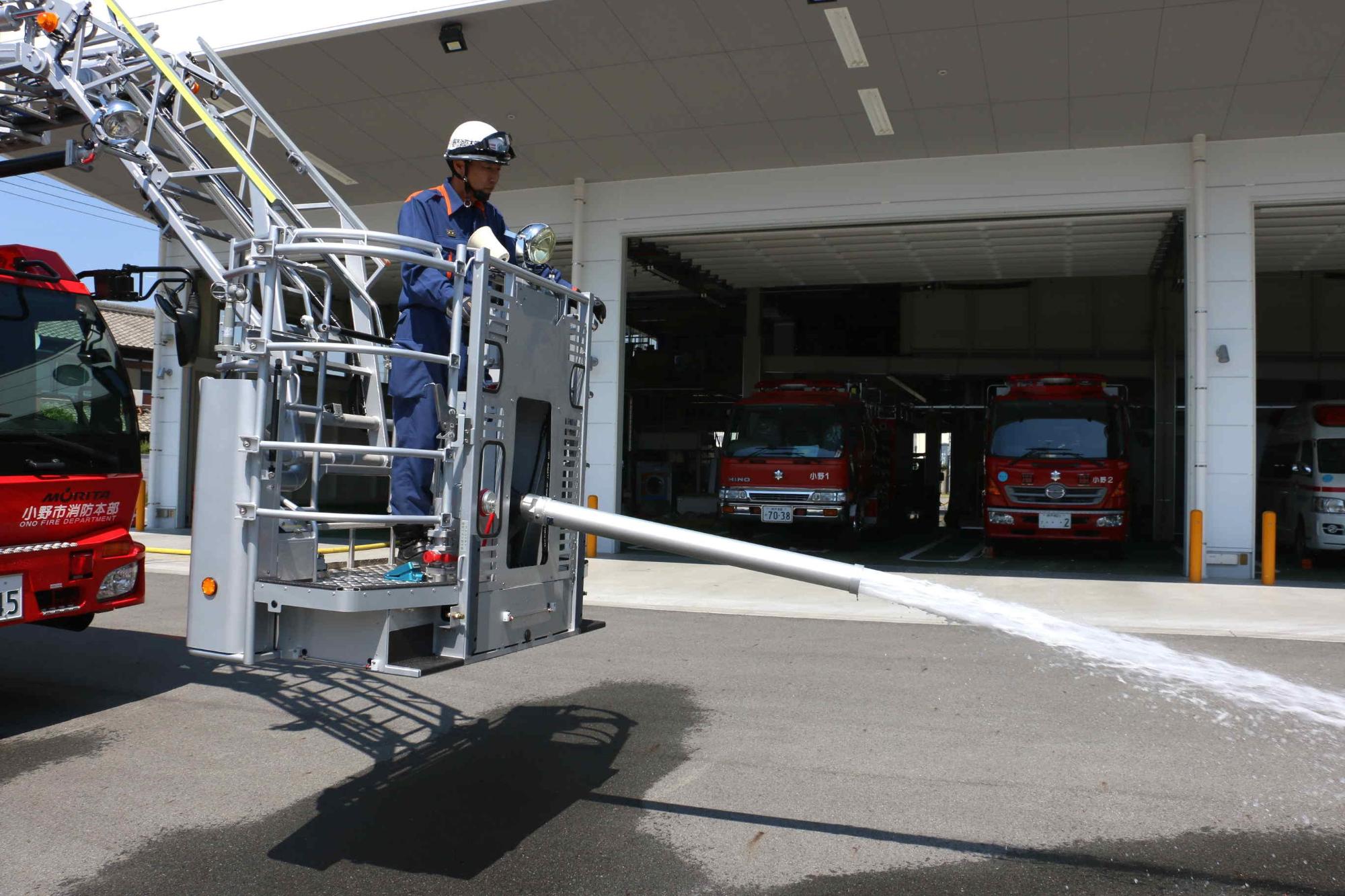 低位置でスケール消防車のバスケットから放水をしている写真