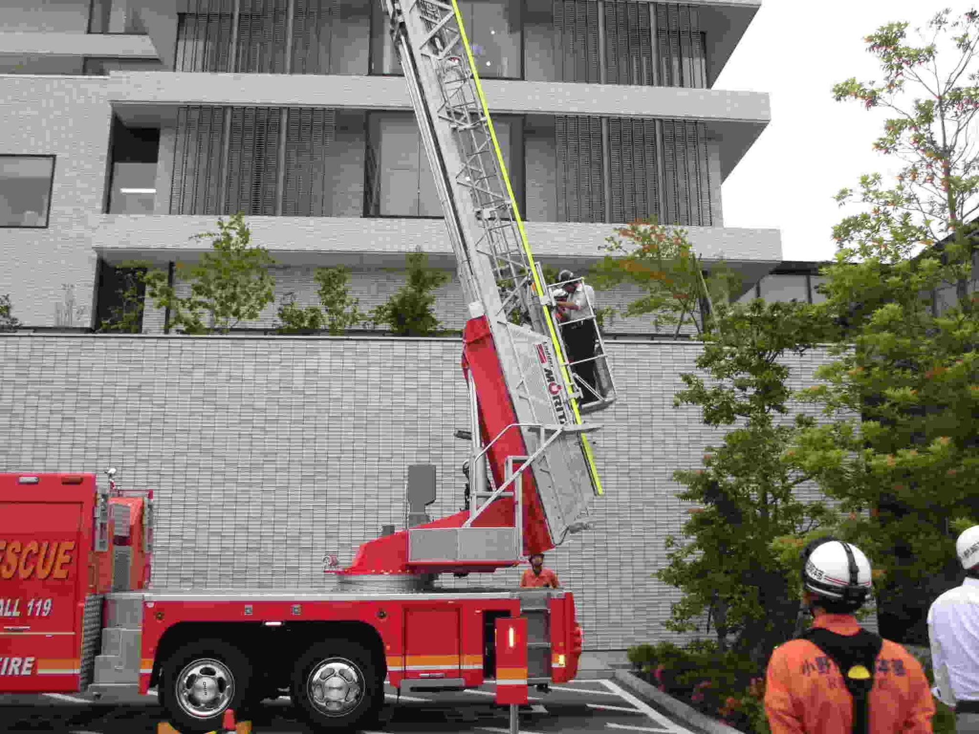 無事に救出しはしご車の自動降下で降りる消防団員と救助者の写真