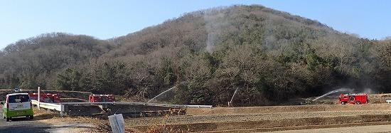 山に向かって消防車などから放水作業を行っている写真
