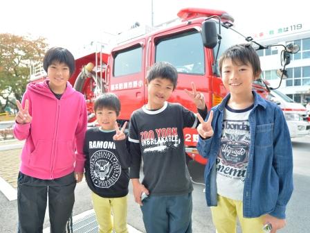 消防車を後ろにピースサインをしながら記念撮影をしている子供たちの写真