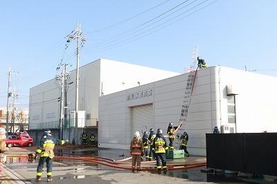 ふたつの白い建物の傍に消防隊員たちが立っている写真