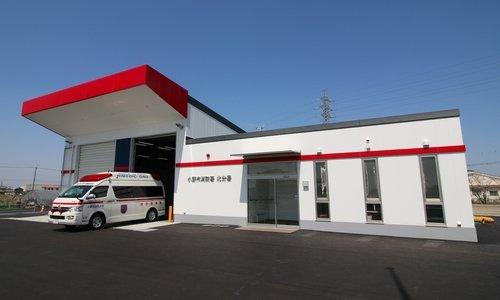 白い壁と赤いひさしの消防署から救急車が出ようとしている写真