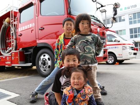 消防車を後ろに縦に並んで記念撮影している子供たちの写真