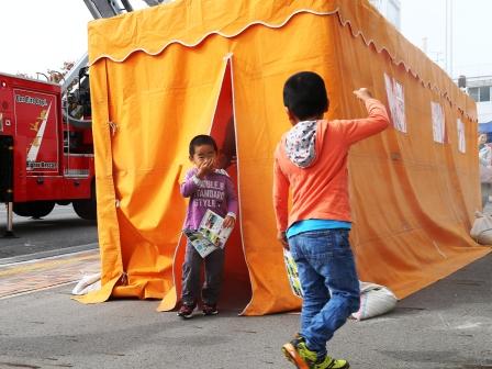 オレンジ色のテントの中で煙避難体験から出てきた2人の子供の写真