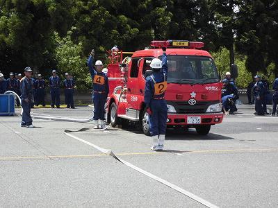 消防車の脇に二人の消防隊員が立っていてお互いに片手を上げている写真