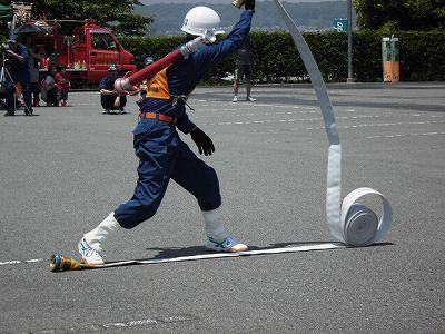 消防隊員が巻かれたホースを広げている写真