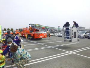 駐車場広場で消防車のはしごのバスケット部分が低い位置まで降りている写真