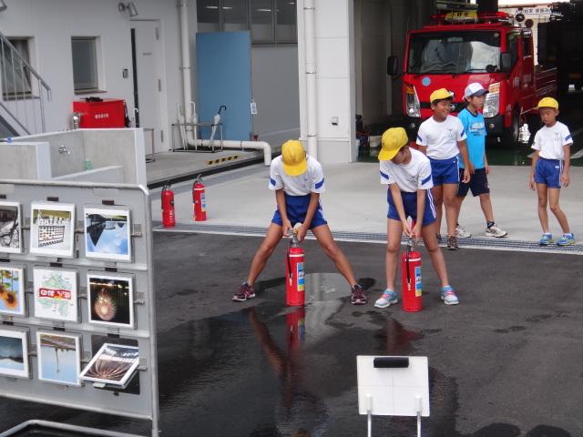 黄色い帽子を被った子どもたちが消火器体験をしている写真