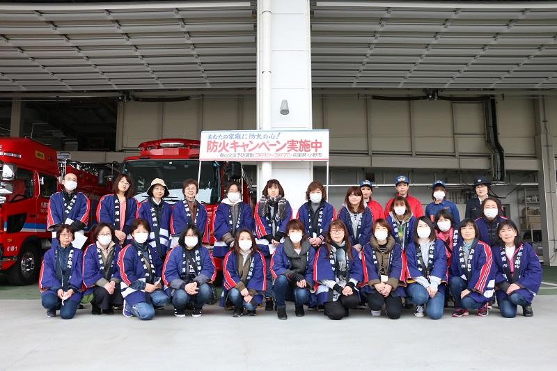 消防署の車庫の前で消防団女性分団員たちが集合している写真