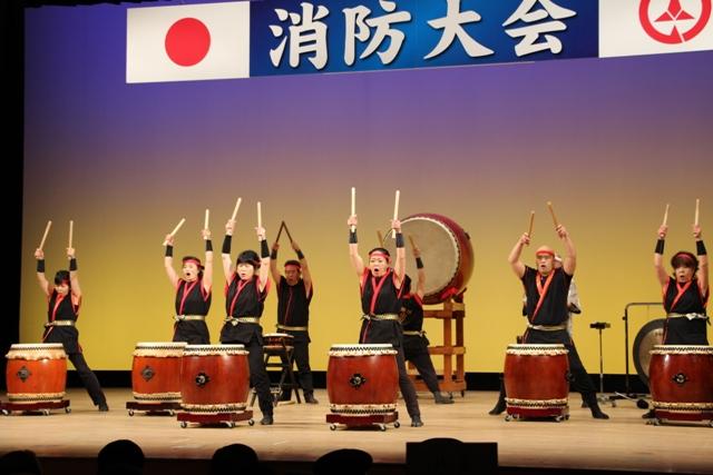 多くの人々がステージ上で和太鼓を演奏している写真