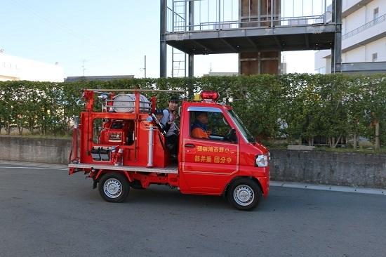 男の子が比較的小さな消防車にのって乗車体験をしている写真