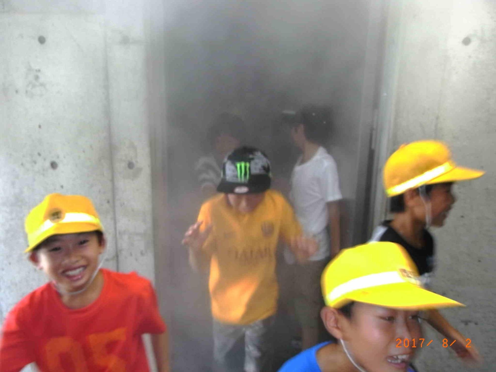 煙が充満している部屋から一斉に避難する生徒たちの写真