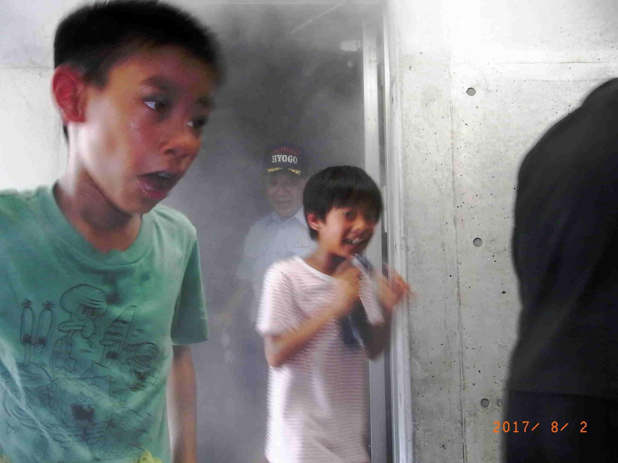 煙が充満している部屋から必死に逃げる2人の子供の写真