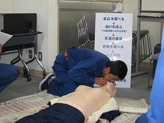 床に置かれた人形を使い人工呼吸の訓練をしている消防団員の写真