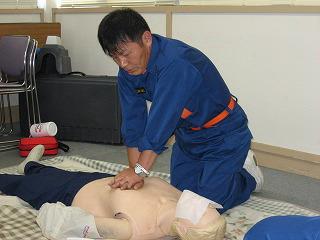 講習会で人形を使い心肺蘇生法を実践している男性の写真
