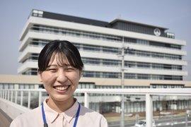 青空の下大きな白い建物をバックに笑顔の西畑 美紅さん