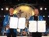 リンゼイ市友好協定書を開いて見せている法被を着たリンゼイ市長と小野市長の写真