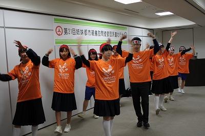 オレンジ色のTシャツを着て赤や白のハチマキをして、ダンスの披露に向け練習に励む団員らの写真